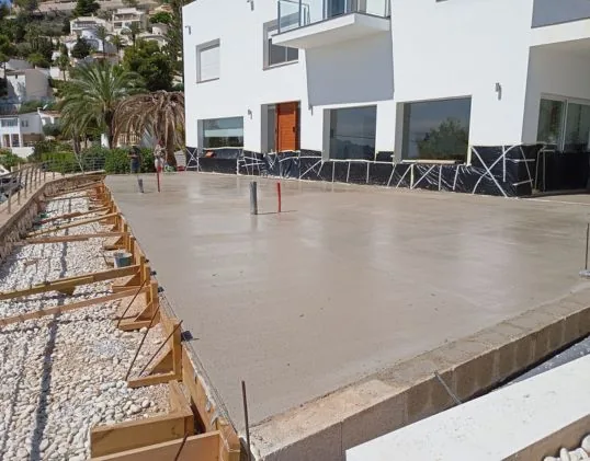 Solera de hormigón recién vertida junto a una villa en Moraira